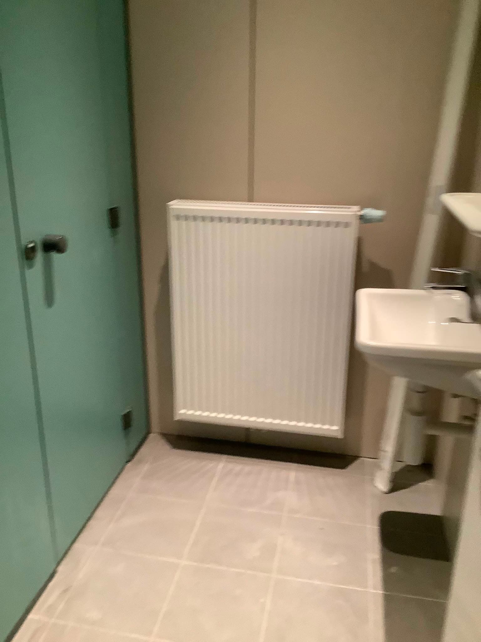 Radiateur panneau neuf posé dans une salle d'eau rénovée, raccordements soignés
