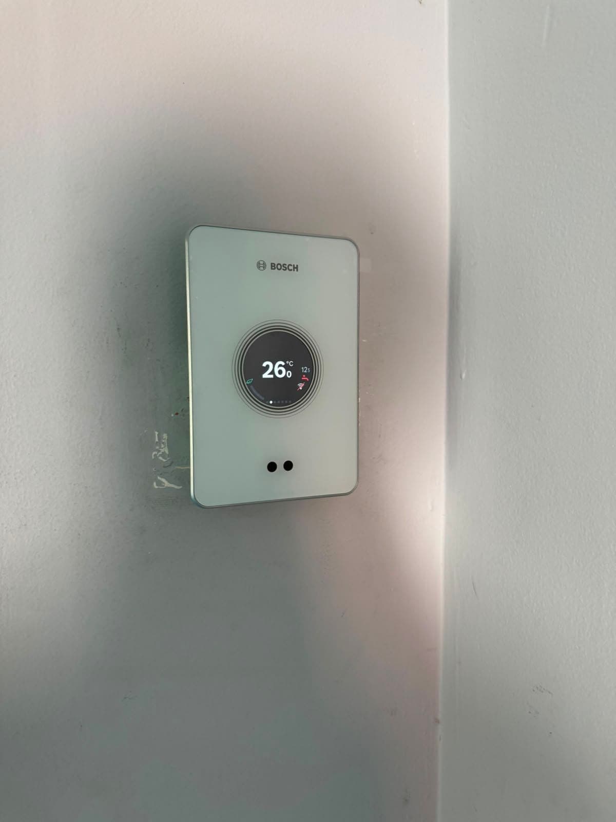 Thermostat d'ambiance connecté Bosch EasyControl posé au mur, écran de température allumé